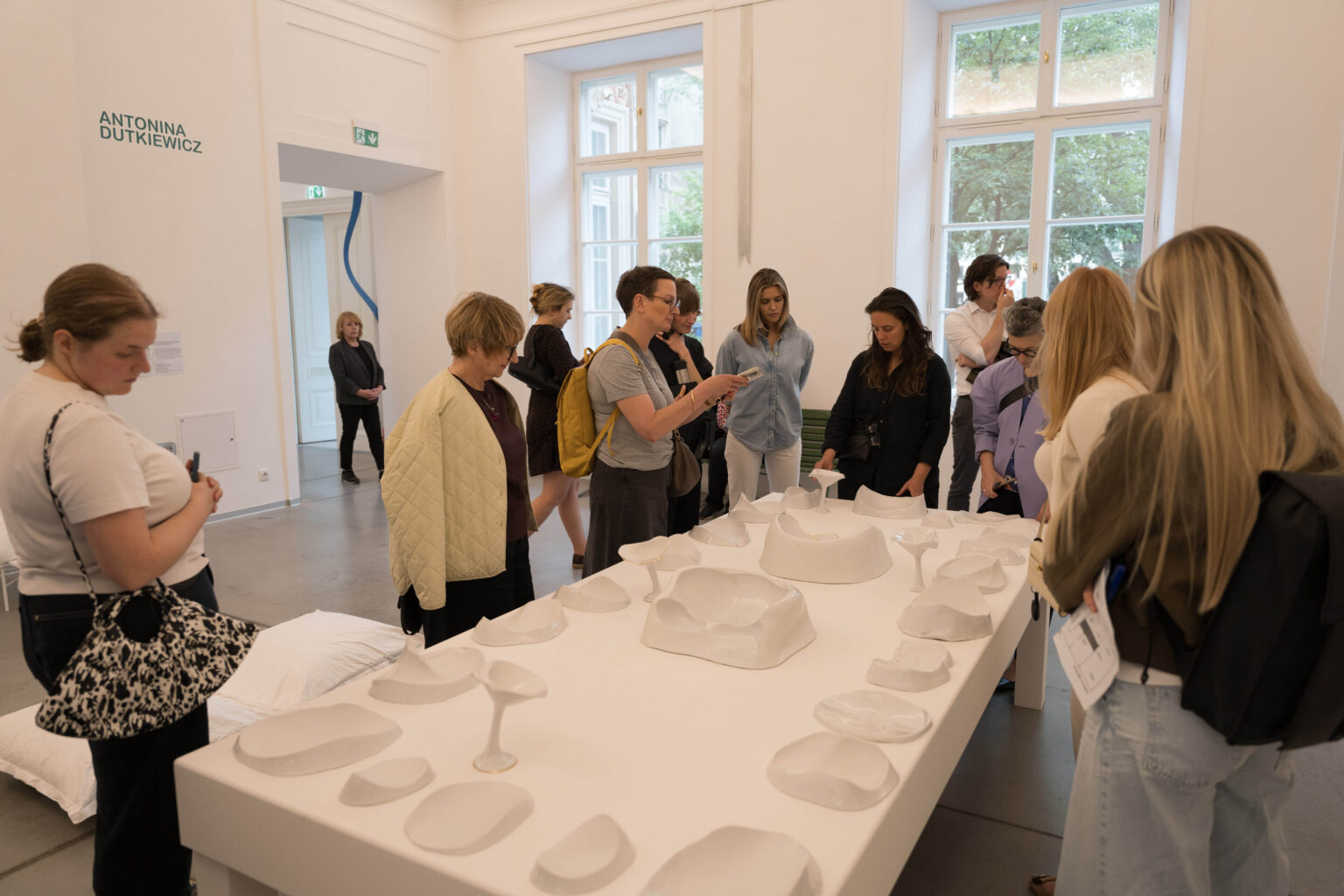 grupa osób przy długim stole zastawionym białymi naczyniami