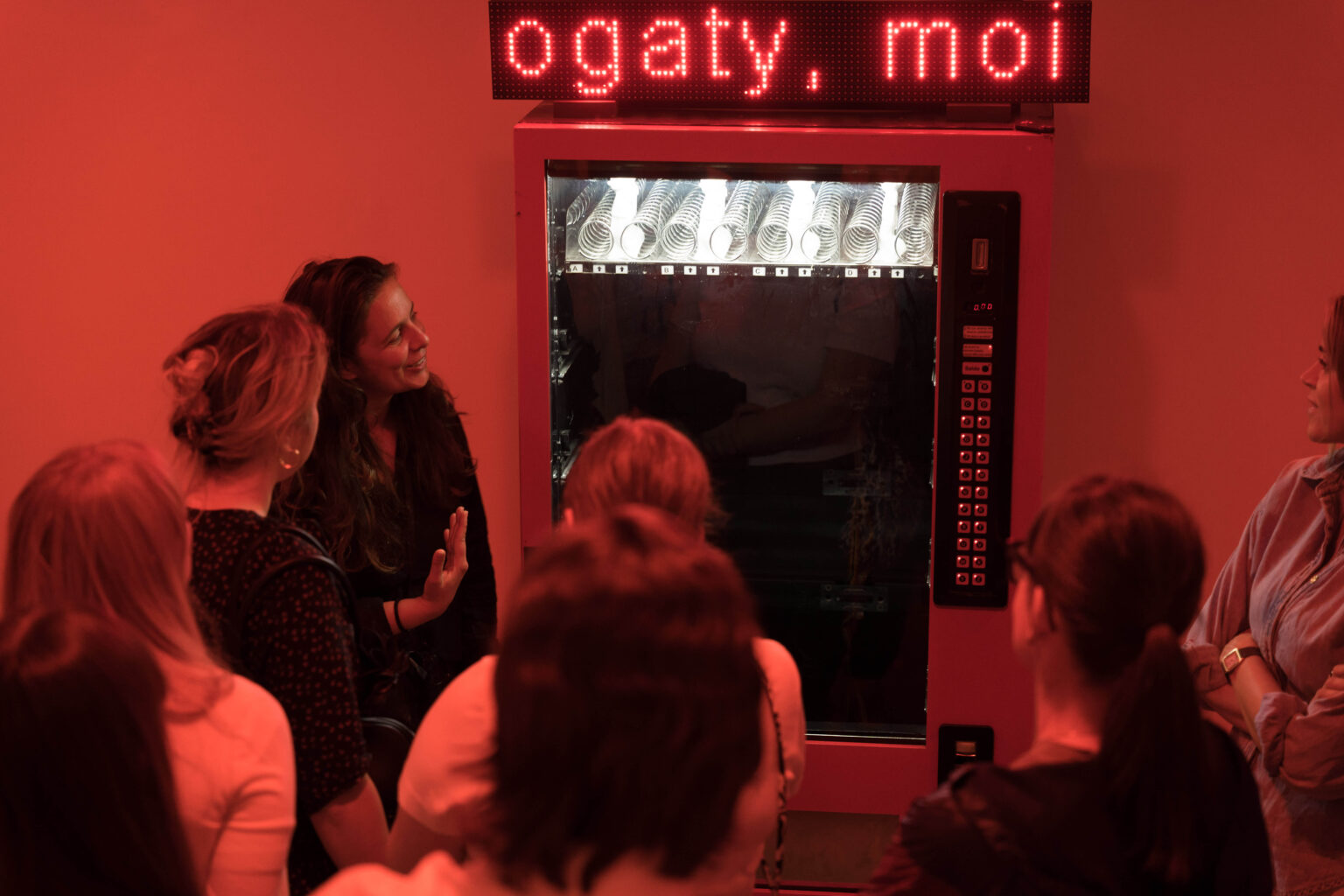grupa osób w przestrzeni wystawy w czerwonym świetle