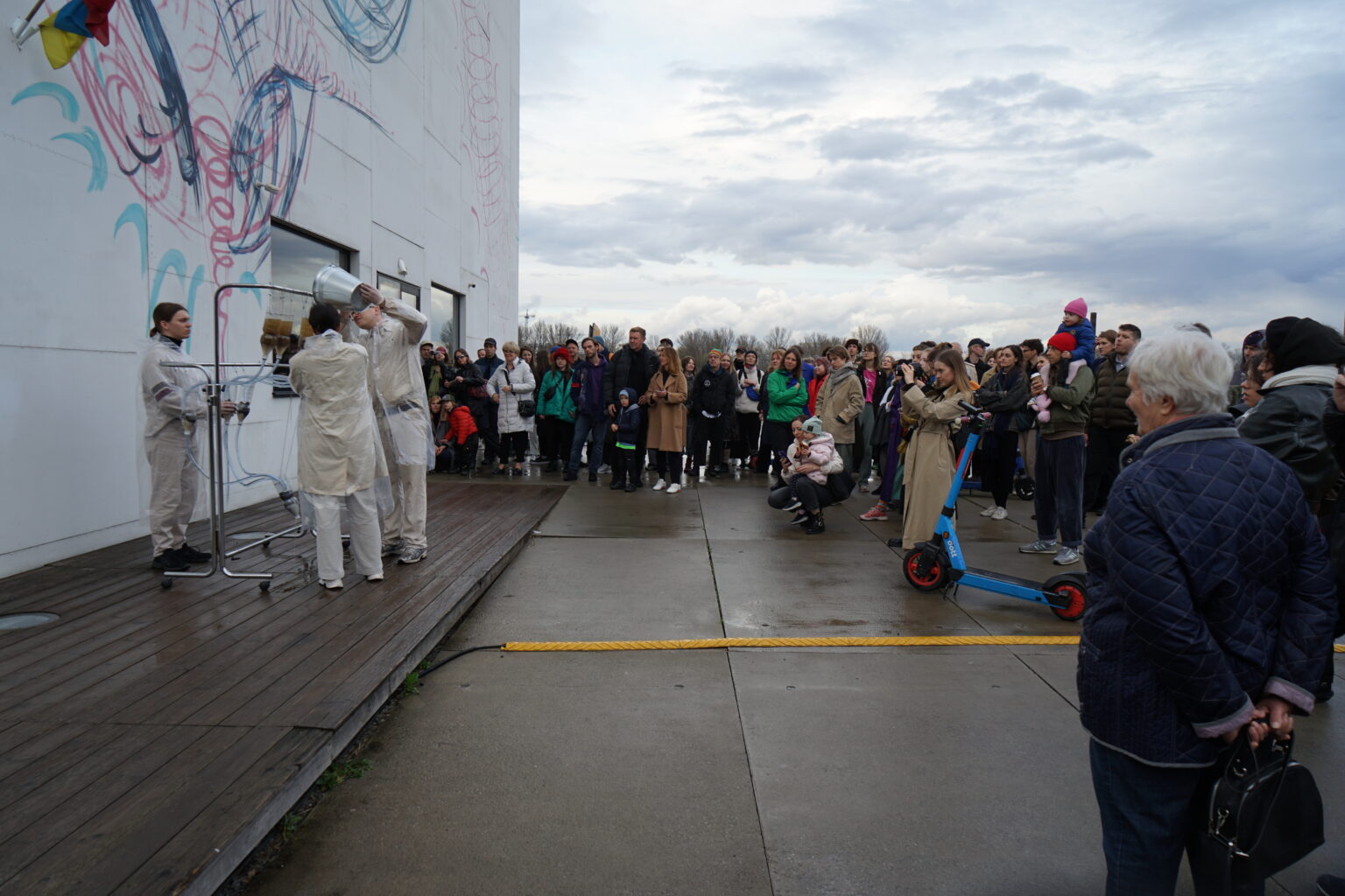 Widok na Muzeum nad Wisłą - Muzeum Sztuki Nowoczesnej w Warszawie, gdzie grupa ludzi obserwuje występ artystyczny na zewnątrz budynku.