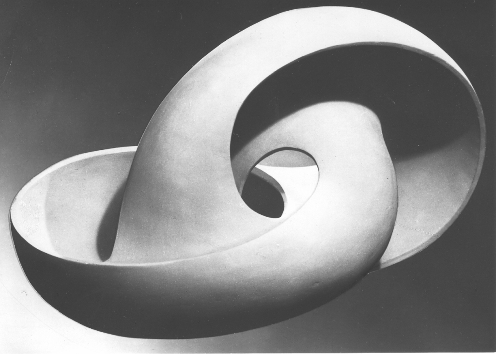 Zdjęcie przedstawia figurę przestrzenną, która wisi w powietrzu. Kształt figury przypomina ucho lub muszlę. Figura jest biała i gładka.