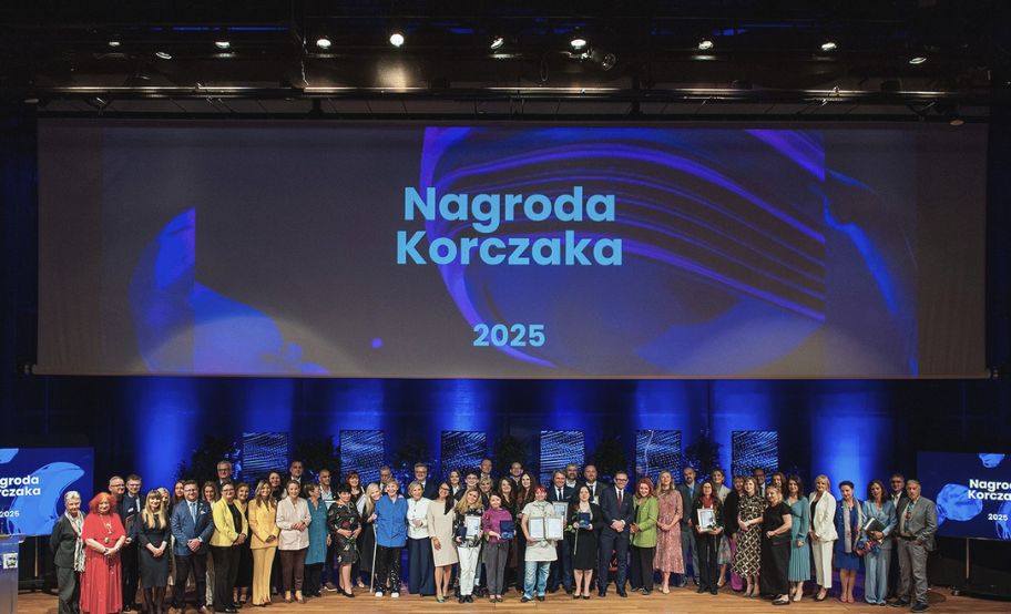 kolorowe zdjęcia uroczystej gali, duża grupa ludzi na scenie, nad nimi wyświetlony napis na niebieskim tle: "Nagroda Korczaka"