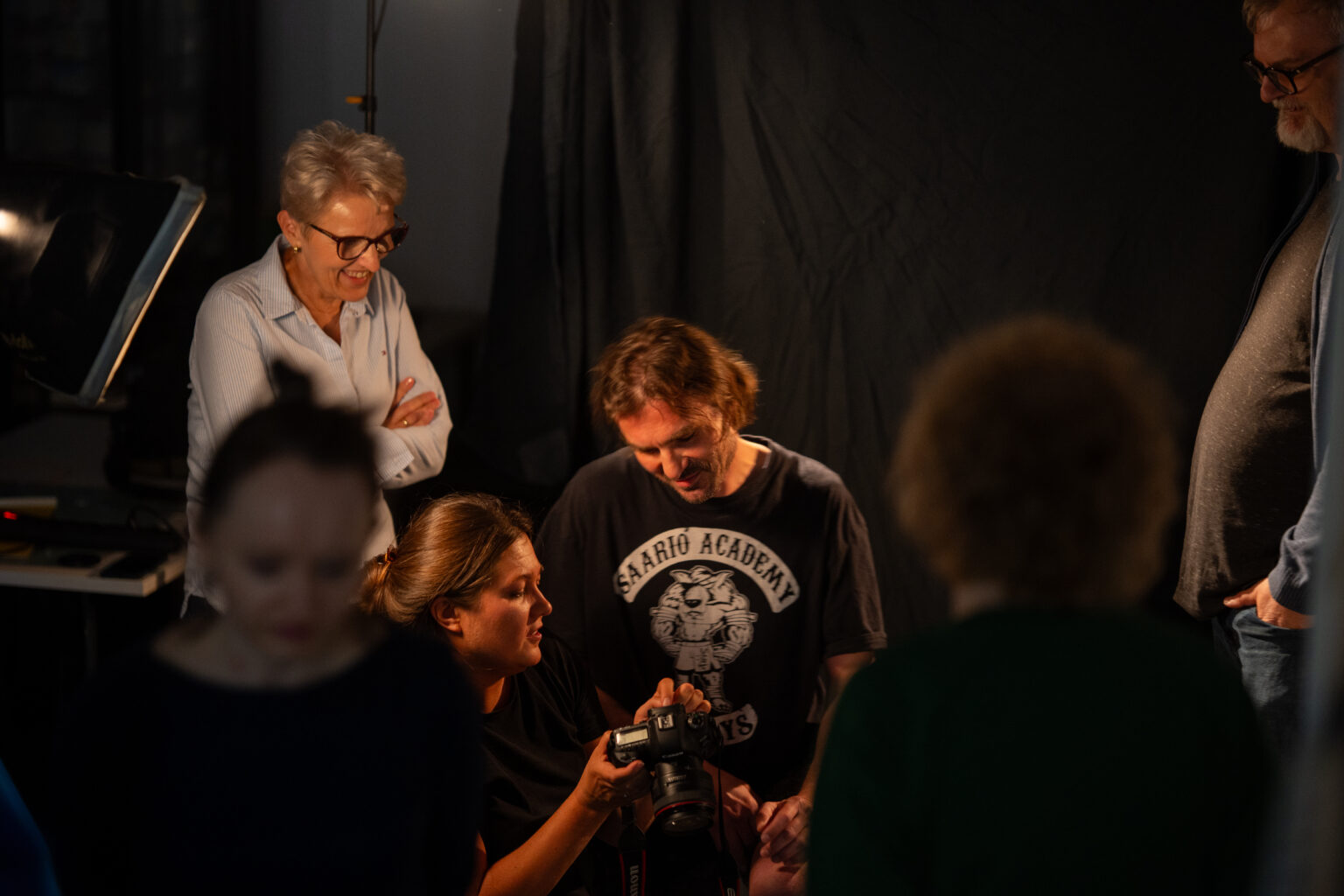 Ludzie oglądają aparat cyfrowy i rozmawiają ze sobą w studiu fotograficznym.