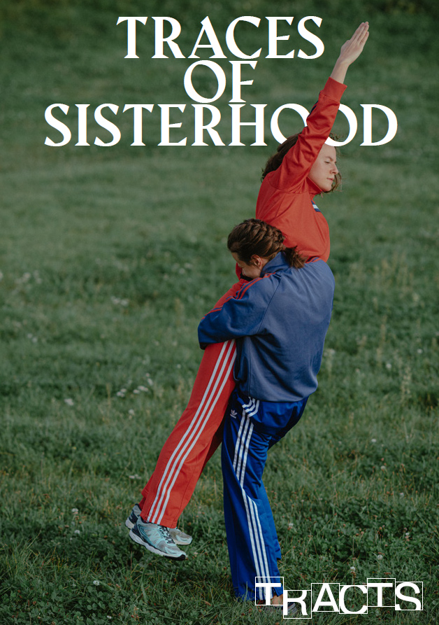 two women in a grassy field. One woman in a red sweatshirt stands on the shoulders of the other, who is wearing a blue sweatshirt. The text at the top reads "TRACES OF SISTERHOOD"