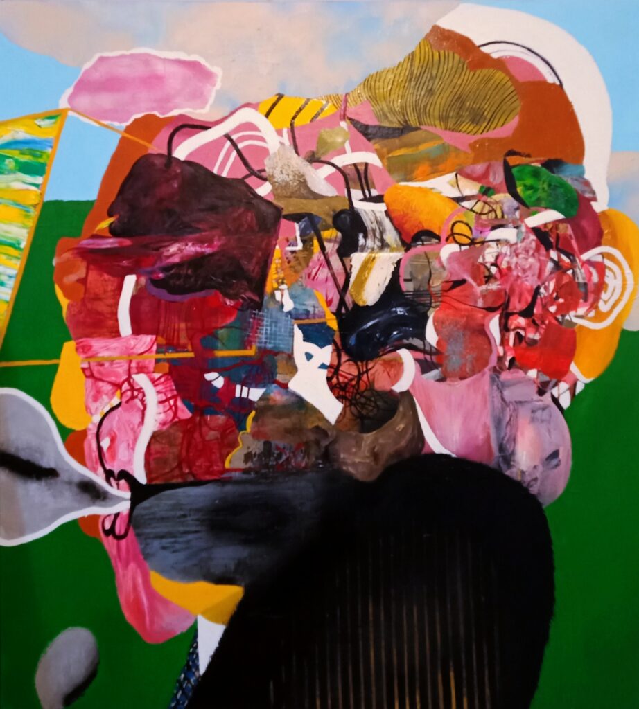 Popiersie w abstrakcyjnej formie. Postać jest pomalowana w żywe kolory, a na jej głowie znajduje się wiele różnorodnych kształtów.